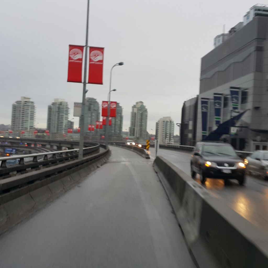 Eine fast leere Straße mit Gebäuden im Hintergrund und ein paar Pfosten in der linken Ecke.