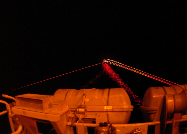 Eine Maschine mit einem roten Laserstrahl, der helles Licht gegen einen dunklen Hintergrund abstrahlt.
