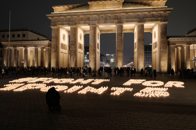 Eine Gruppe von Menschen, die vor dem beleuchteten Reichstagsgebäude in Berlin, Deutschland, mit der Aufschrift "Kampf für die Freiheit" im Vordergrund stehen.