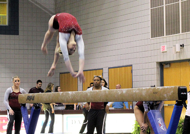 Eine Frau führt Gymnastik an der Spitze des Bildes aus, mit mehreren Personen unten, einer Wand im Hintergrund, Fenstern und Türen auf der rechten Seite und einem Tisch unten.