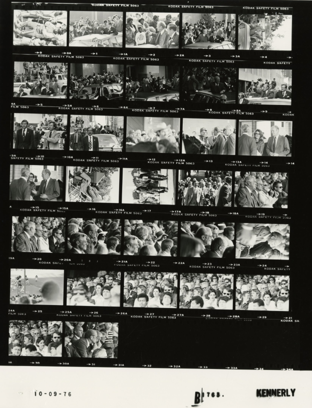 Schwarzes und weißes Foto einer vielseitigen Menge, die lachend auf einen Fernseher schaut.