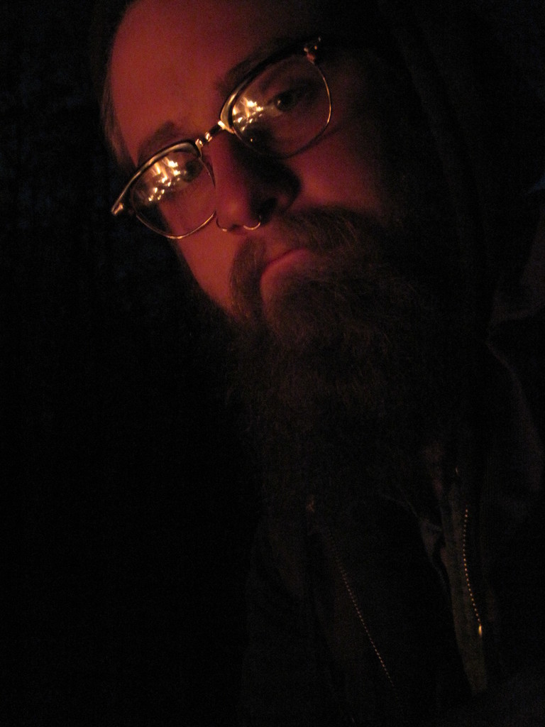 Ein Mann mit einem großen Bart und Brille posiert direkt in die Kamera.