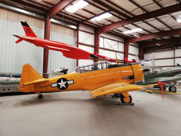 Ein großer Hangar voller verschiedener Flugzeugtypen, mit einer Wand im Hintergrund und Lampen oben, im National Museum of the United States Air Force.