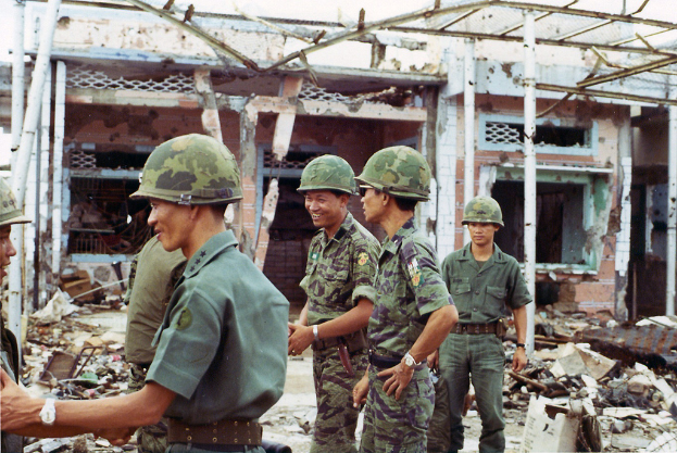 Ein demoliertes Haus mit ein paar Soldaten in der Nähe.