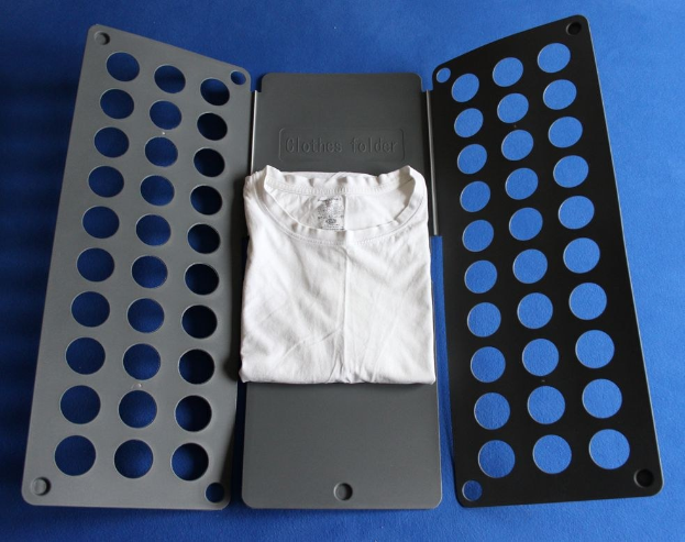 Weißes T-Shirt auf blauer Oberfläche neben schwarzem und aschfarbenem Kleiderordner mit Löchern.