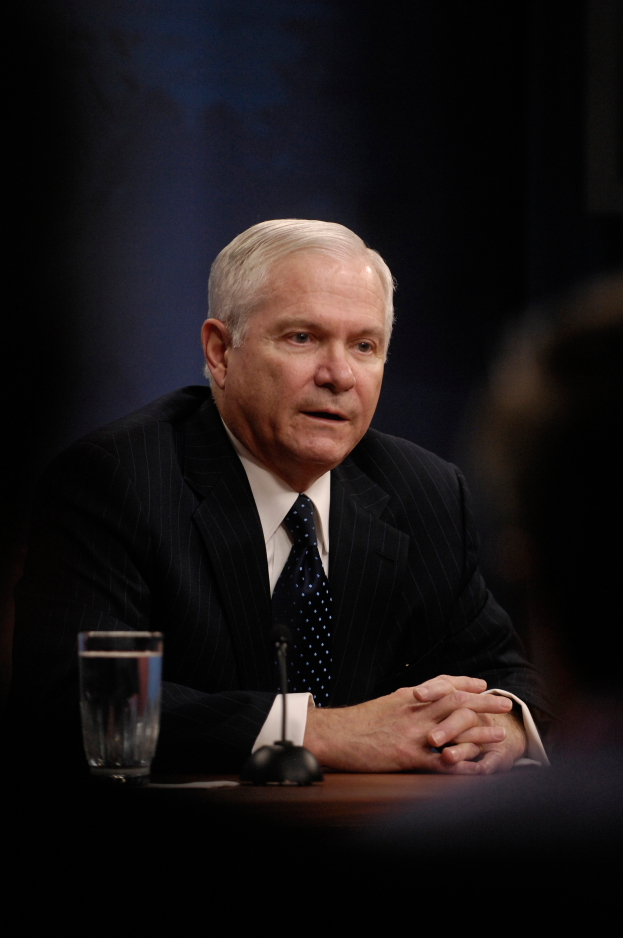 Ein Mann im Anzug und Krawatte sitzt an einem Tisch mit einem Glas Wasser und einem Mikrofon und sieht ernst aus wie ein Generalstaatsanwalt.