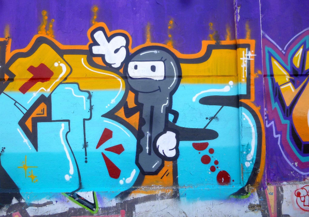 Eine Wand voller bunter, farbenfroher Graffiti mit einem leuchtenden Cartoon-Charakter in verschiedenen Formen und Größen.