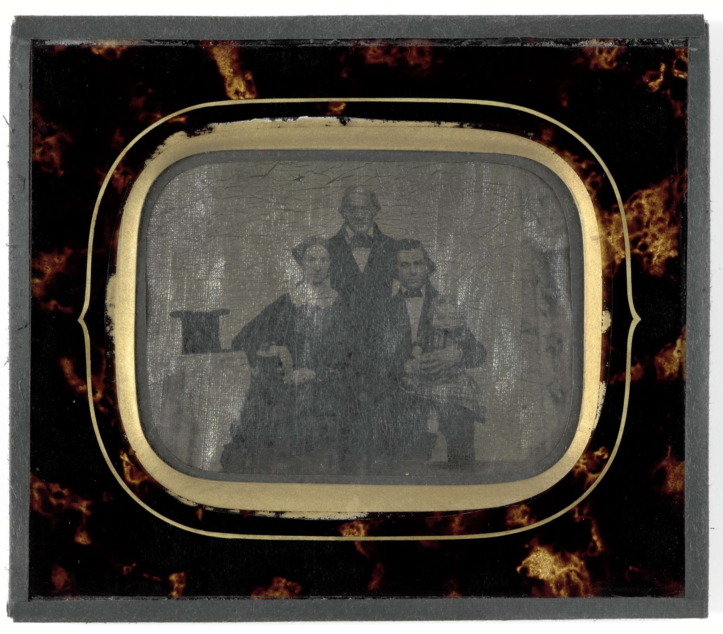 Schwarze-Weiß-Foto eines Mannes im Anzug und einer Frau in unbekannter Kleidung vor einem Fernseher mit ernsten Gesichtern.