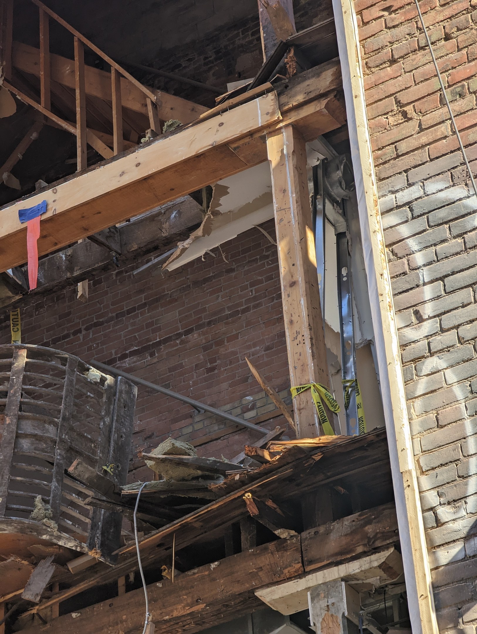Ein teilweise abgerissener Bau mit verstreuten Holzplanken und Trümmern, zerbrochene Fenster und Türen, was auf die Nachwirkungen einer Abrissarbeiten hindeutet.