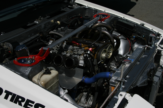 Ein Auto-Motor mit sichtbaren Rohren und einer Batterie.