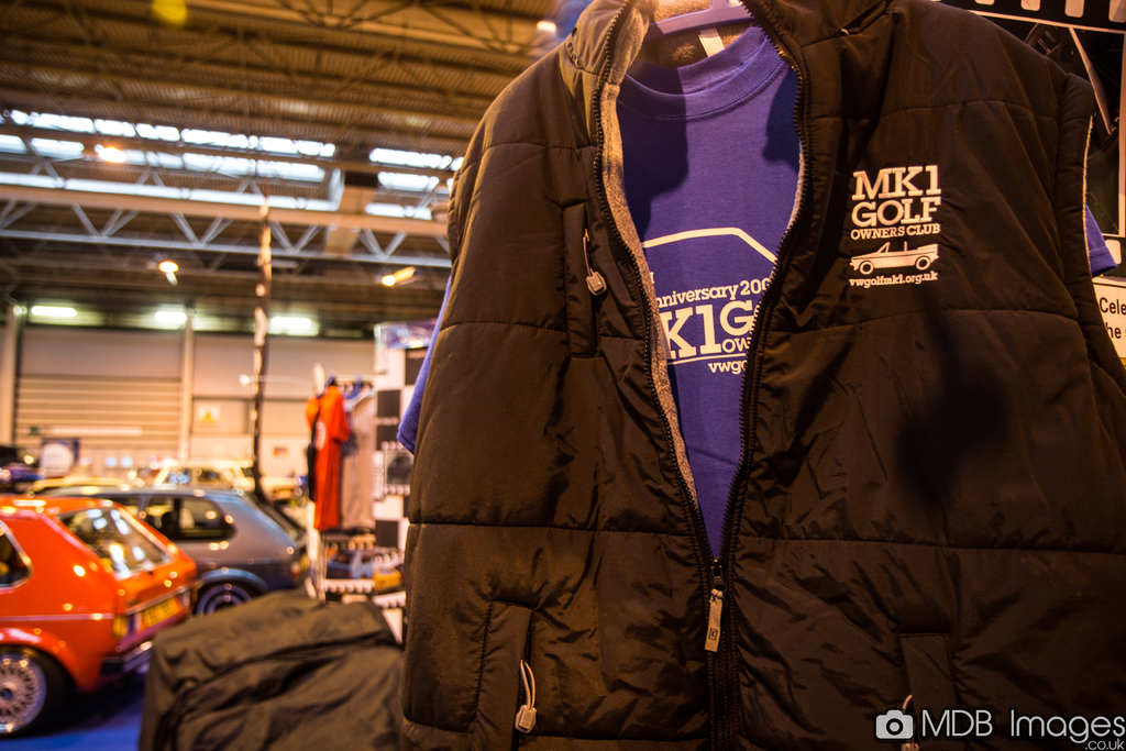 Eine Jacke ist im Vordergrund zu sehen, mit Autos, Lampen und Polen im Hintergrund und einer Wand noch weiter hinten.