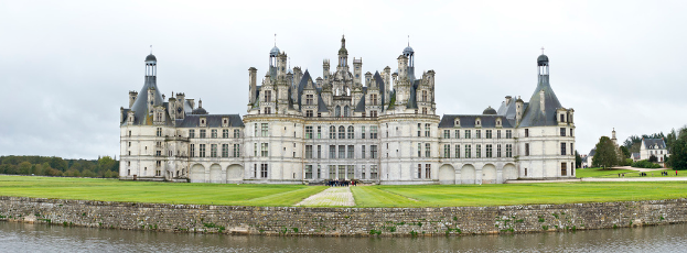 Ein prächtiger Palast steht in der Mitte des Bildes, mit einem Hintergrund aus Bäumen und einem Gewässer unten.