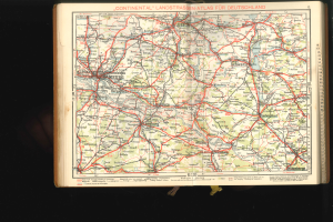Ein aufgeschlagenes Buch mit einer detaillierten Karte von Deutschland mit Straßen und Autobahnen auf einem dunklen Hintergrund.