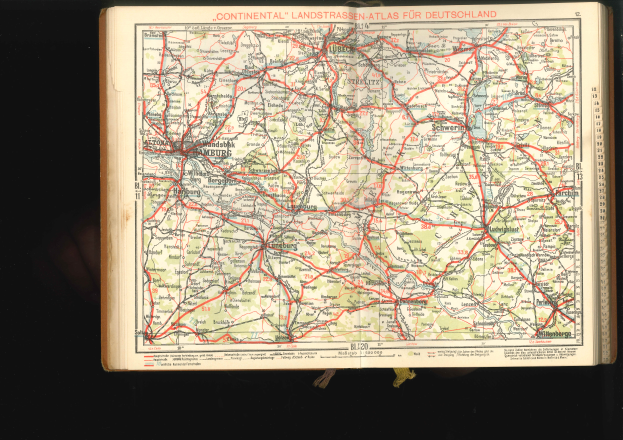Ein aufgeschlagenes Buch mit einer detaillierten Karte von Deutschland mit Straßen und Autobahnen auf einem dunklen Hintergrund.