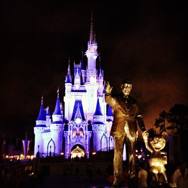 Statuen auf der rechten Seite, Cinderella-Schloss im Hintergrund und verstreute B√§ume im Bild.