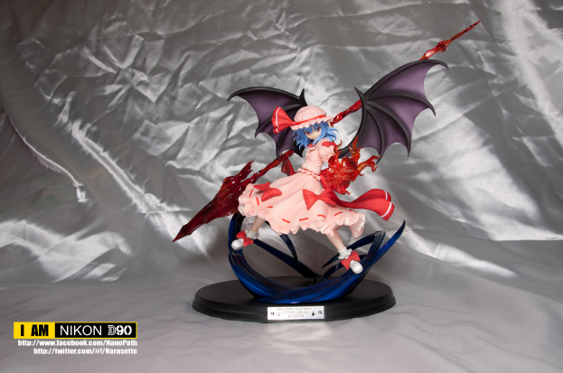 Ein Spielzeug liegt auf einem silbernfarbenen Tuch mit sichtbaren Wasserzeichen auf dem Bild.