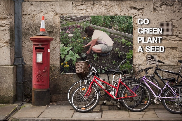 Fahrräder in der Nähe einer Briefkasten mit einer Sicherheitstonne darauf, eine Wand mit einem Plakat und Text im Hintergrund und ein Weg am unteren Rand des Bildes.
