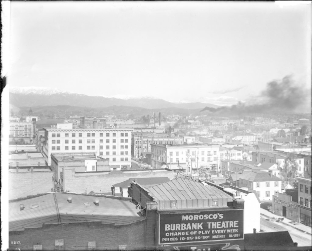 Ein Schwarz-WeiÃŸ- Bild einer Fabrik mit Rauch, der aus dem Schornstein kommt, umgeben von GebÃ¤uden.