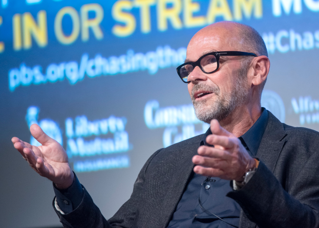 Steve Ballmer, ein Mann im Anzug und mit Brille, spricht in ein Mikrofon mit einem Bildschirm im Hintergrund.