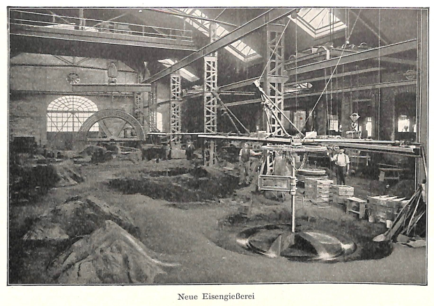 Schwarzes und weißes Foto eines Fabrikinneren mit Arbeitern, die Maschinen bedienen, Metallstangen und -stangen, beschriftet mit "Neue Eisengießerei, die erste Fabrik in Deutschland" unten.