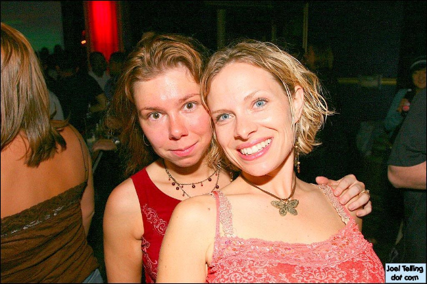 Eine Gruppe von Menschen mit zwei strahlenden Frauen in der Mitte und einem Licht im Hintergrund.