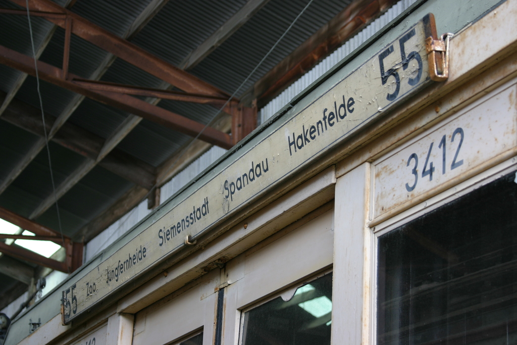 Ein kleiner Laden mit einer Namensschilder und einem Metallrahmenverschlag darüber.