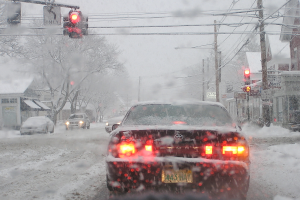 Eine ruhige, schneebedeckte Straße mit Bäumen und Häusern auf beiden Seiten unter einem klaren Himmel.